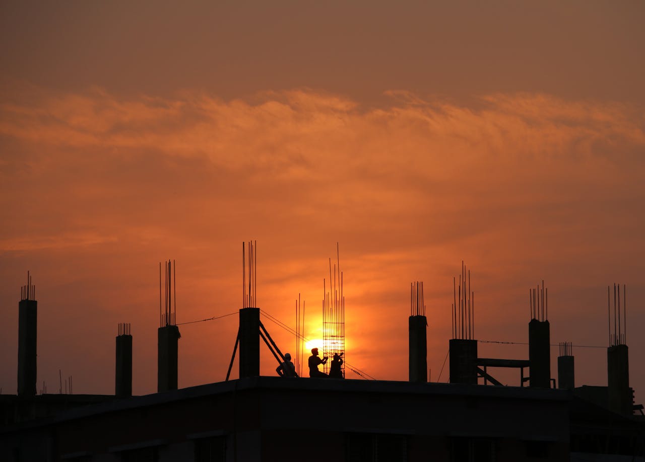 Crafting Captivating Headlines: Your awesome post title goes here 1 Silhouette of workers on a construction site against a vibrant sunset sky.