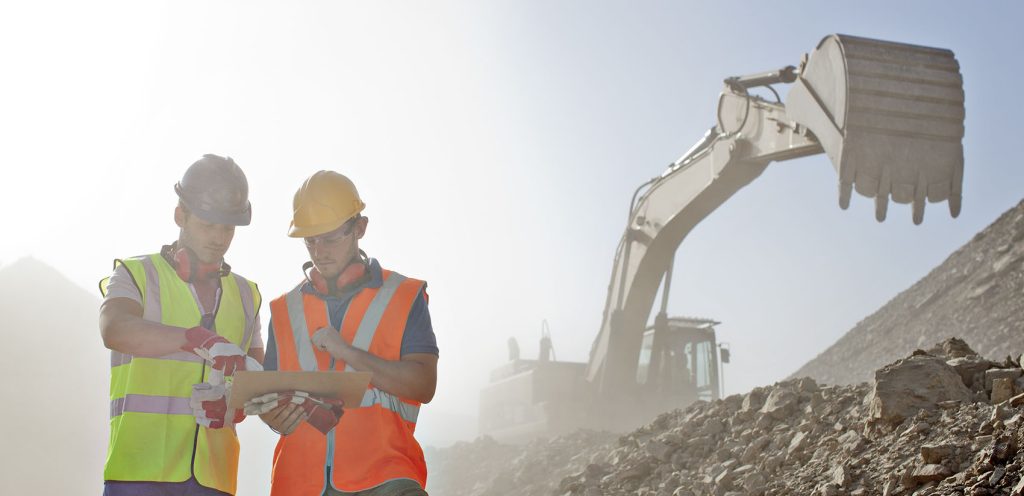 Workers reading blueprints in quarry construction workers hard hat